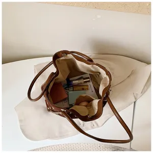 Vue détaillée d'un sac cabas marron en toile, montrant un grand espace et des accessoires.