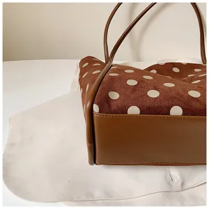 Détail de cabas à pois marron, montrant une texture daim douce et un fond en cuir robuste.