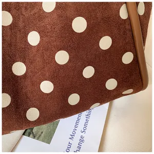 Gros plan d'un élégant sac cabas en suédine marron à pois, texture douce et bordure en cuir.