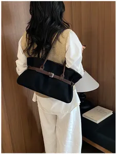 Black tote bag detail showing brown shoulder straps and stylish waist belt buckle design.