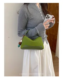 Detailansicht der stilvollen grünen Colorblock-Handtasche mit schickem Anhänger.