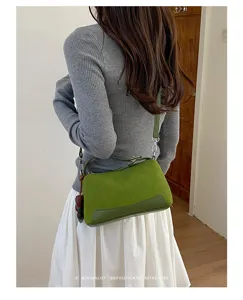 Detailansicht der stylischen grünen Kontrast-Umhängetasche mit eleganten Nähten und Riemen.