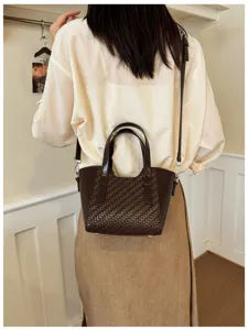 Vue détaillée du sac bandoulière tissé élégant, mettant en valeur le cuir texturé.