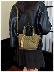 Vue détaillée du sac porté épaule tressé vert olive foncé avec charm en perles de bois.