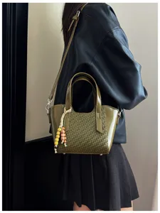 Gros plan détaillé du sac à main élégant en cuir tressé vert olive avec pendentif en perles.