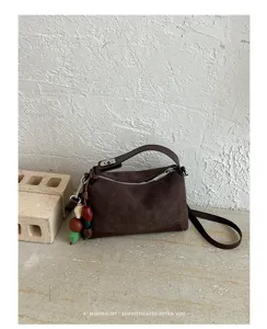 Koreanischer Retro-Stil braune Schulterhandtasche mit Henkel und schicken Deko-Anhängern.