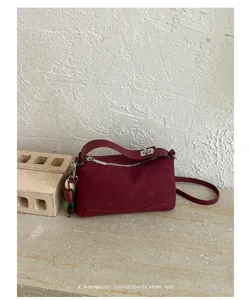 Detailaufnahme der retro bordeauxroten Schultertasche mit Schloss und reicher Textur.