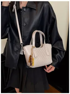 Vue détaillée du sac bandoulière tissé beige, avec une texture élégante et une poignée pratique.
