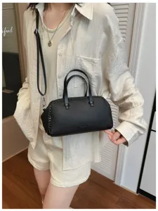 Gedetailleerd overzicht van een zwarte kunstlederen Boston tas met gevlochten zijdetails.