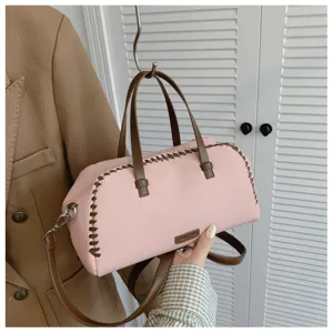 Close-up van roze Boston handtas met bruine contraststiksels en afneembare schouderriem.