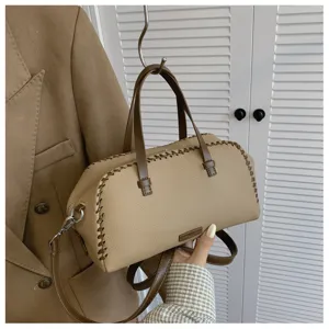 Close-up detail van de stijlvolle beige handtas met contraststiksels en stevige handvatten.