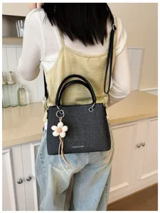 Vista detallada de un elegante bolso bandolera gris oscuro con textura y asas elegantes.
