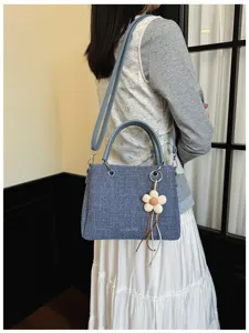 Bolso de mano chic de tela azul con asa y abalorio floral, elegante bolso cruzado.