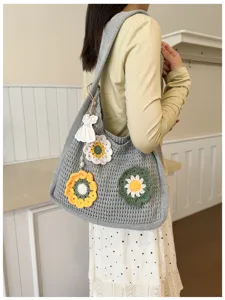 Detail view of grey crochet tote bag featuring handmade flower patches and cute pendant.