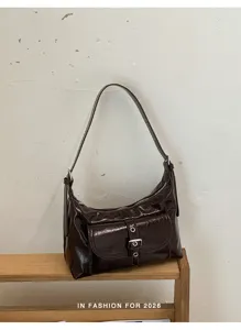 Dettaglio della borsa a spalla retrò in vernice con tasca frontale e fibbia in metallo.
