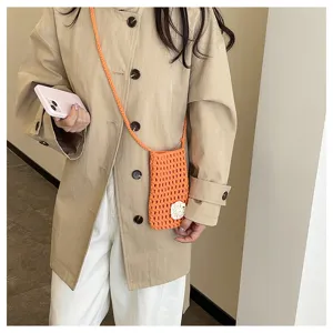 Nahaufnahme einer niedlichen orangefarbenen Häkel-Handytasche mit floralem Detail.