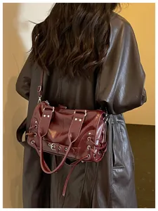 Nahaufnahme der dunkelroten Ledertasche mit Metallschnalle, Nieten und Schnürdetails.
