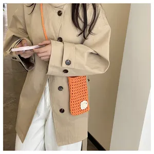 Nahaufnahme der handgemachten gehäkelten Handytasche in Orange mit Blumenakzent.