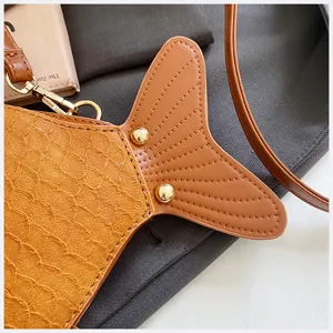 Close-up detail shot of cute creative fish shaped PU leather crossbody bag in brown color.