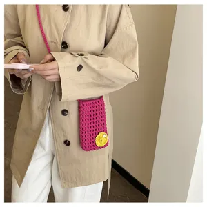 Detailansicht der handgefertigten Häkel-Handytasche in hellem Pink mit gelbem Blumenakzent.