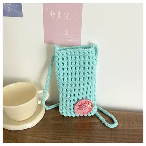 Nahaufnahme Detailansicht der hellblauen handgefertigten Häkelhandy Tasche mit Blüte.