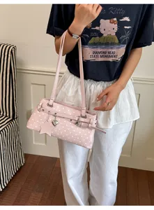 Detailed shot of pink polka dot shoulder bag with cute charms and belt buckle design.