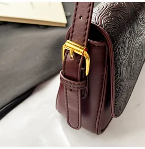 Close-up detail of women vintage embossed leather shoulder bag with gold metal buckle.