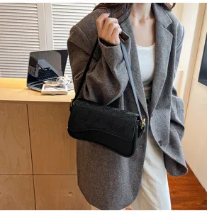 Detailed view of the stylish black embossed shoulder bag worn with a chic grey blazer.