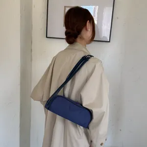 Korean minimalist solid color cylindrical underarm shoulder bag shown from back view.