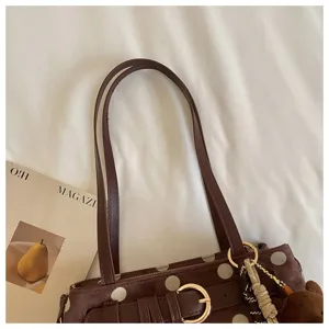 Détail de sac baguette à pois marron, sac bandoulière vintage avec pendentif ours.