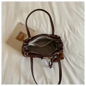 Chic sac baguette marron à pois avec pendentif ours, élégant fourre-tout pour femme.