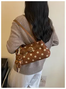 Vue détaillée du sac d'épaule marron à pois avec un joli pendentif d'ours tendance.