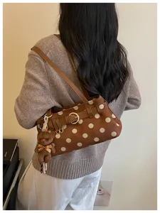 Vue détaillée du sac baguette marron à pois avec charmant pendentif ours en peluche.