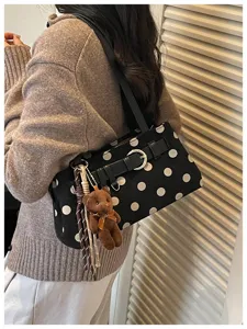 Vue de détail du sac baguette élégant à pois noirs avec charmant accessoire d'ours en peluche.
