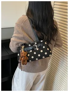 Gros plan sur le sac à épaule noir chic à pois avec un joli détail de porte-clés.
