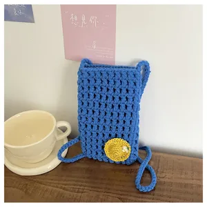 Handgemachte Häkel-Handytasche Detail, blaues Hohlstrick-Design mit süßem Strohhut-Charm Sommer.