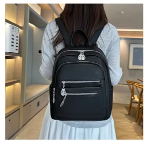 Detailed shot showing the black leather backpack's multiple zipper pockets and back wear.