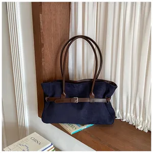 Detail view of a large capacity retro tote bag in dark blue suede with brown leather belt.