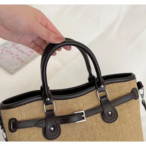 Detail view of stylish straw tote bag with brown leather trim and metal buckle accent.