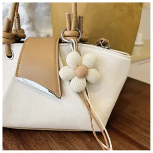 Nahaufnahme einer stilvollen zweifarbigen Eimer-Tasche mit Stoffblumen-Anhänger und Leder.