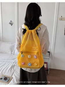 Yellow mesh drawstring backpack detail showing colorful flower decorations and back view.