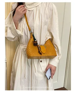 Stilvolle gelbe gewebte Schultertasche für Damen, Retro Achseltasche mit Schnalle und Anhänger.