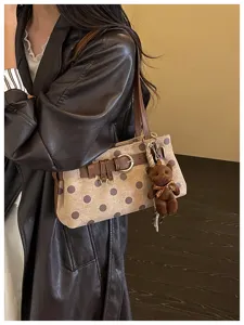 Vue détaillée du sac baguette élégant à pois marron avec un joli pendentif ours en peluche.