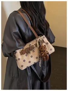 Vue détaillée du sac à épaule tendance à pois avec joli pendentif ours et lanière chic.