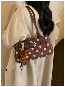 Vue détaillée du sac baguette marron à pois avec pendentif d'ours mignon et bandoulière.