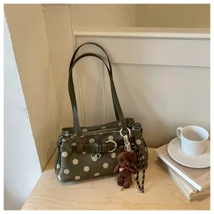 Vue détaillée de la pochette baguette vert foncé à pois avec joli pendentif ours.