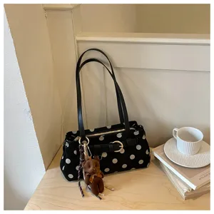 Vue détaillée du sac baguette noir à pois avec un joli pendentif ours en peluche.