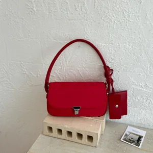 Red shoulder baguette bag for women, minimalist chic commuting handbag with knot accent.