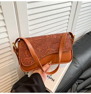 Close-up detail view of the vintage brown embossed leather shoulder bag flap and strap.