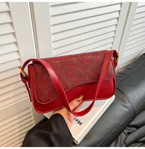 Detailed view of the vintage red embossed leather shoulder bag showcasing exquisite floral tooling.
